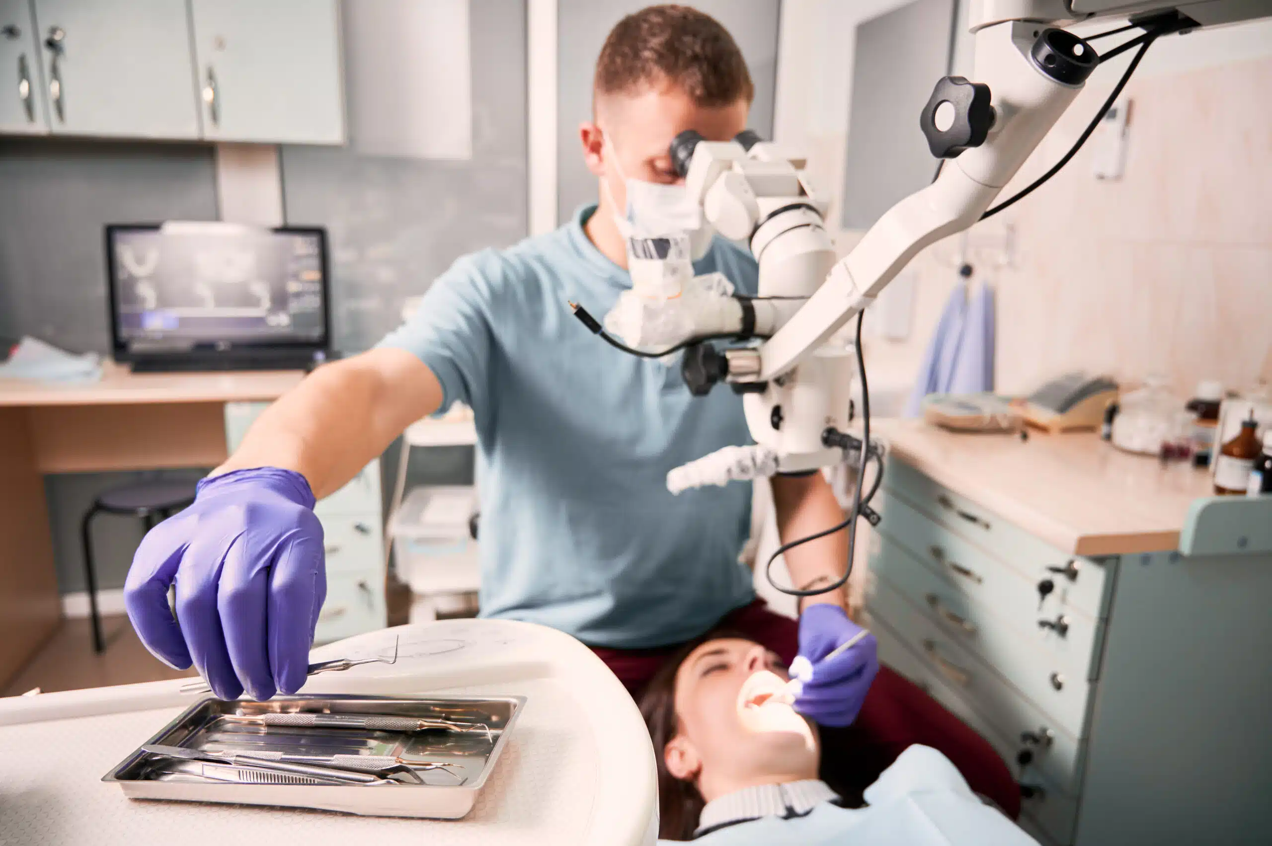 Male dentist grabbing dental explorer during dental procedure.