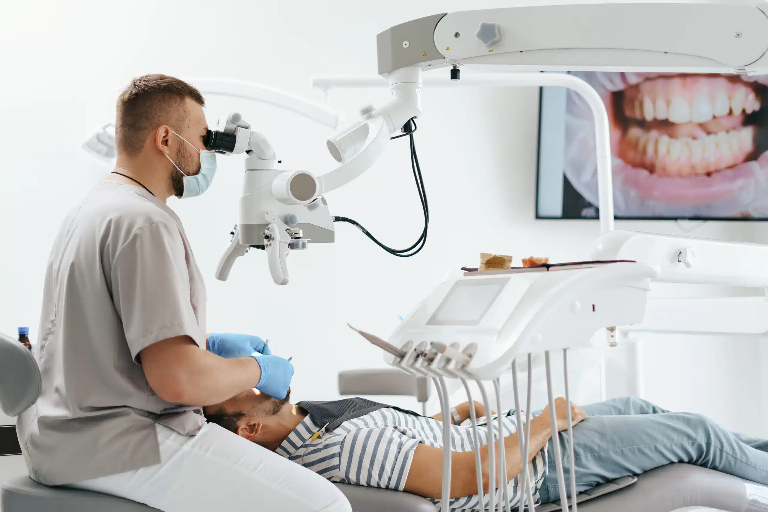 Male dentist wearing mask looking in the microscope